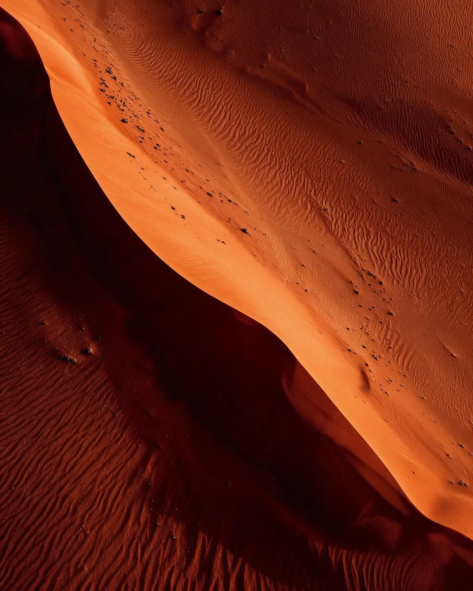 A red dune from directly above, one lit edge running through it